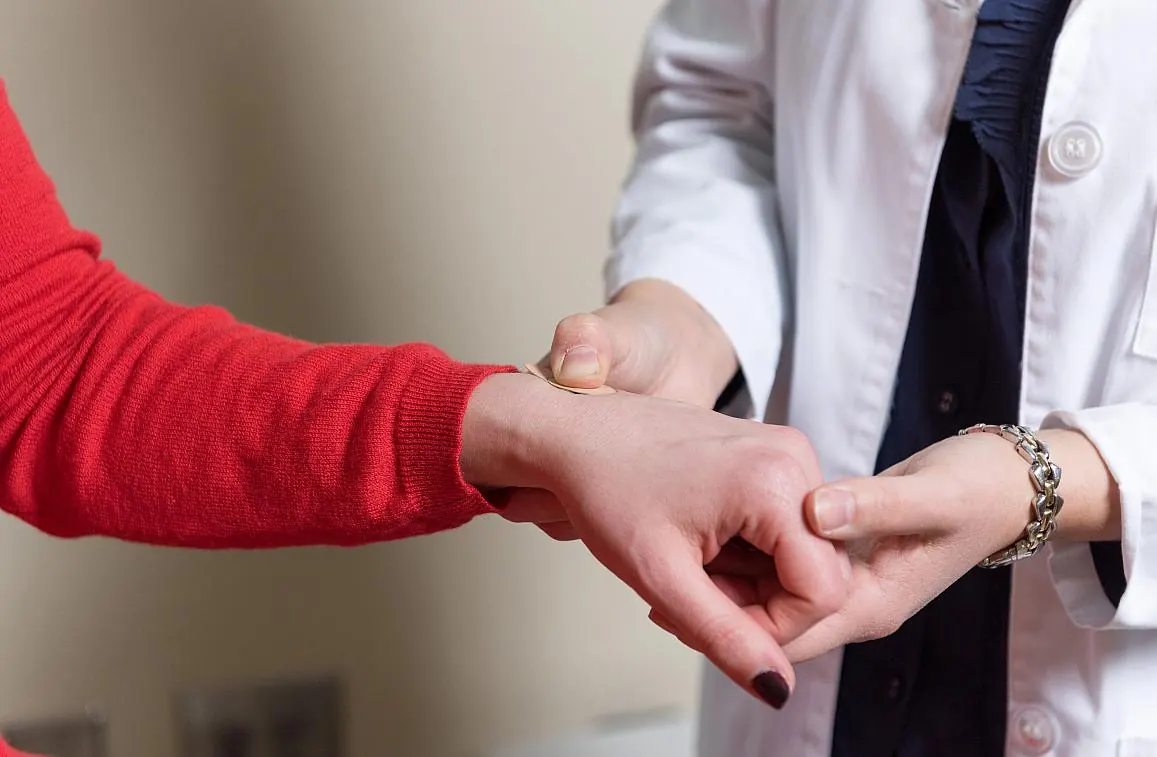 A clinician's hands examining a patient's wrist