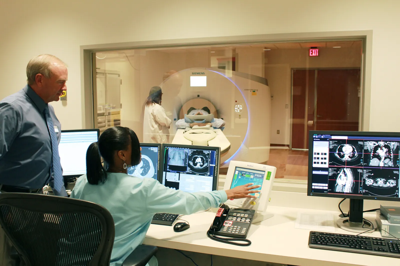 A radiology reading room with scans on several screens